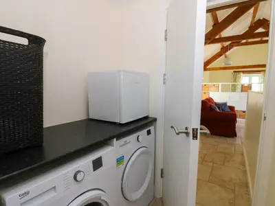 a kitchen with a washer and dryer in a room at Cwtch in Ystrad Meurig