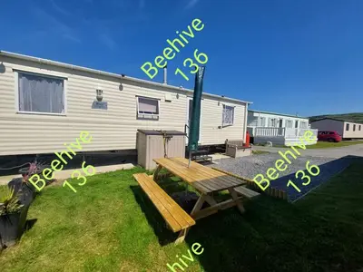 a picnic table in the grass in front of a trailer at Beehive 136 snowdon summit 100 in Barmouth