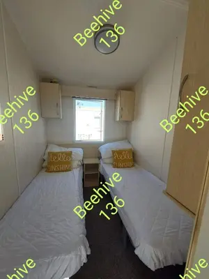 a small room with two beds and a clock on the wall at Beehive 136 snowdon summit 100 in Barmouth