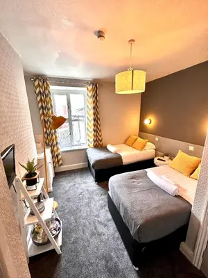 a small room with two beds and a tv at gwesTY Guest House in Aberystwyth