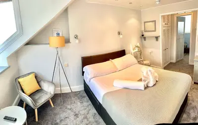 a small bedroom with a bed and a chair at gwesTY Guest House in Aberystwyth