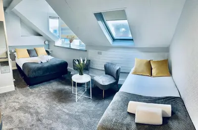 a attic bedroom with two beds and a chair at gwesTY Guest House in Aberystwyth