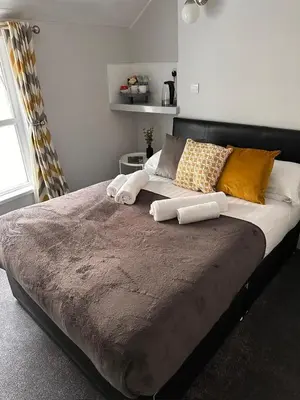 a large bed with pillows on it in a bedroom at gwesTY Guest House in Aberystwyth