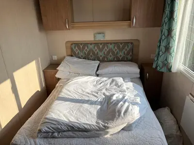 an empty bed in a small room with a window at The Lookout 3 Bedroom Family Caravan Pet Friendly in Aberystwyth