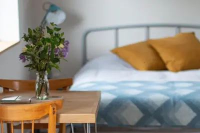 a vase of flowers on a table next to a bed at Beautiful Cabin Near Hay-on-Wye in Peterchurch