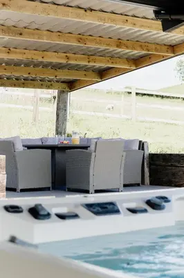 a patio with a table and chairs under a wooden roof at Cambrian Farm House by Birch Stays in Devils Bridge