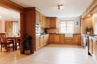 a large kitchen with wooden cabinets and a table at Cambrian Farm House by Birch Stays in Devils Bridge