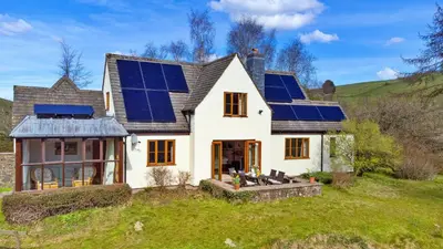 a house with solar panels on the roof at Finest Retreats - Cwmfron House in Llanidloes