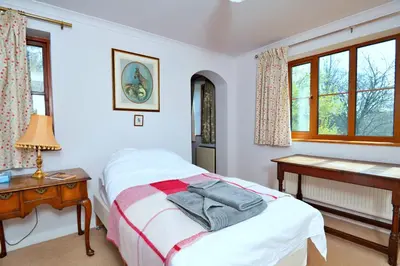 a bedroom with a bed and a desk and windows at Finest Retreats - Cwmfron House in Llanidloes