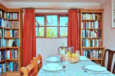 a dining room with a table with bookshelves at Finest Retreats - Cwmfron House in Llanidloes