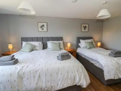 two twin beds in a bedroom with two lamps at Curtau in Builth Wells