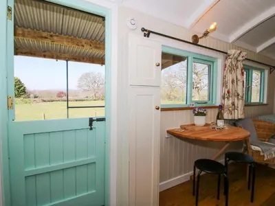 a door leading into a tiny house with a table at Gilberry Shepherds Hut in Church Stretton