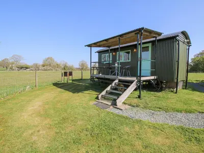 a green tiny house with a slide in a field at Gilberry Shepherds Hut in Church Stretton