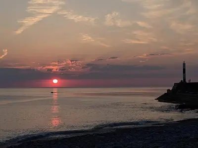 a sunset over the ocean with a boat in the water at Duplex apartment with spectacular sea views! in Aberystwyth