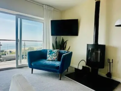 a living room with a blue chair and a fireplace at Verbier Luxurious Seaside Retreat in Aberdyfi