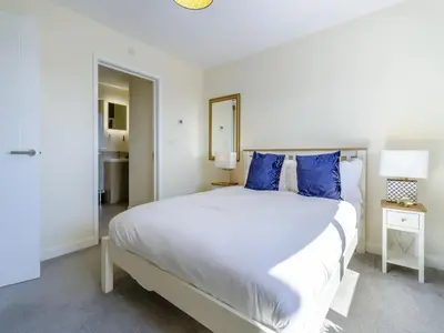 a bedroom with a large white bed with blue pillows at Verbier Luxurious Seaside Retreat in Aberdyfi