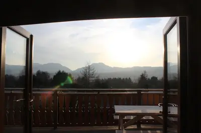a view of the mountains from a balcony with a picnic table at Beautifully Restored Log Cabin in Trawsfynydd