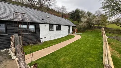 a white house with a fence next to a yard at Peaceful Dyfi Valley Cottage - Hendre-gau in Machynlleth