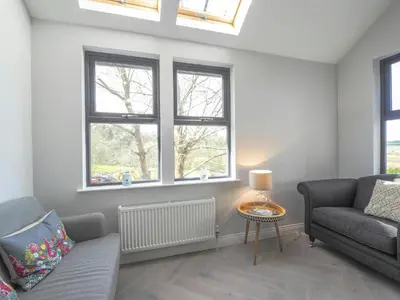 a living room with a couch and two windows at Ceirios Wen Aberaeron in Llanarth