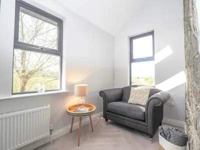 a living room with a chair and a table at Ceirios Wen Aberaeron in Llanarth