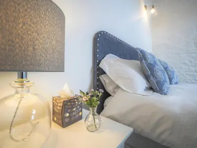 a bed with a lamp and a vase of flowers on a table at Ceirios Wen Aberaeron in Llanarth