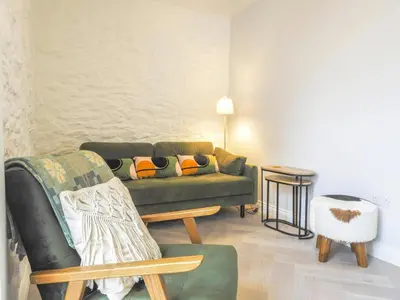a living room with a green couch and a chair at Ceirios Wen Aberaeron in Llanarth