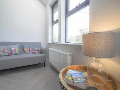 a living room with a table with a lamp and a couch at Ceirios Wen Aberaeron in Llanarth