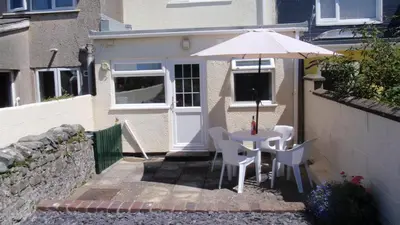 a table and chairs with an umbrella in front of a house at Geraig Aberaeron in Aberaeron