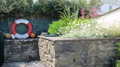 a garden with a red life preserver and some flowers at Geraig Aberaeron in Aberaeron