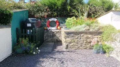 a garden with a gate and a stone wall at Geraig Aberaeron in Aberaeron