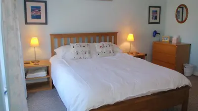 a bedroom with a large white bed with two lamps at Geraig Aberaeron in Aberaeron
