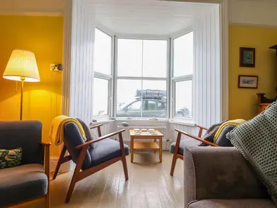 a living room with two chairs and a table and a window at Beach Haven in Aberystwyth