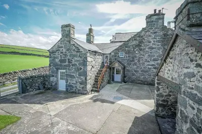 an old stone building with a door and a grass field at Gegin-Faeldre in Llanbedr