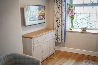 a living room with a tv and a window at Gegin-Faeldre in Llanbedr