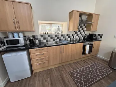 a kitchen with wooden cabinets and a sink and a dishwasher at Coastal Bliss Charming Cottage near Borth beach in Borth