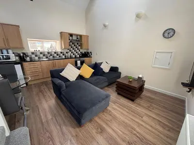 a living room with a couch and a kitchen at Coastal Bliss Charming Cottage near Borth beach in Borth