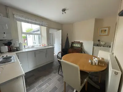 a kitchen with a wooden table and a dining room at Cosy Cottage in Kington
