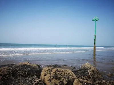 a pole in the ocean with rocks in the water at Delightful Chalet Peaceful Site Near Aberdyfi in Tywyn