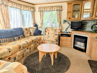 a living room with a couch and a table at Family-Friendly Woodland Caravan Pool & Bar in Bryn-glâs Station