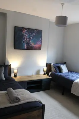 a bedroom with two beds and a desk with a deer on the wall at Charming 4-Bed in Llangollen in Llangollen