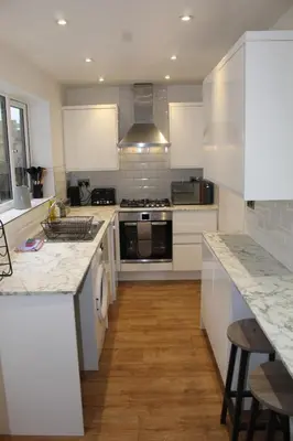 a kitchen with white cabinets and a stove top oven at Charming 4-Bed in Llangollen in Llangollen