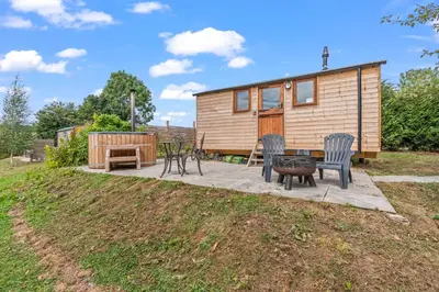 a tiny house with a patio and a table and chairs at Off-Grid Glamping - Quiet, Starry Escape in Yarpole