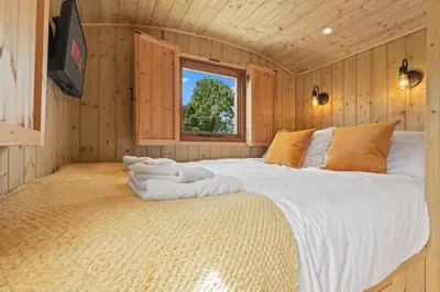 a bedroom with a large bed in a wooden room at Off-Grid Glamping - Quiet, Starry Escape in Yarpole