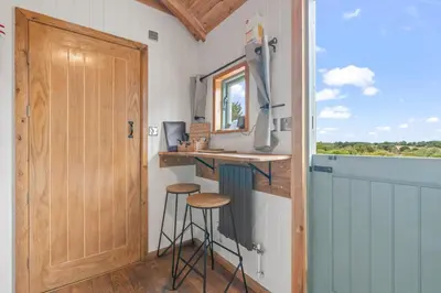 a tiny house with a bar and stools in it at Hot Tub Luxury Glamping - Private Stargazing Patio in Yarpole