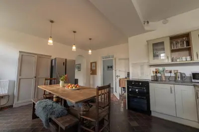 a kitchen with a wooden table with chairs and a tableasteryasteryasteryasteryastery at Coach House in Llanwrtyd Wells