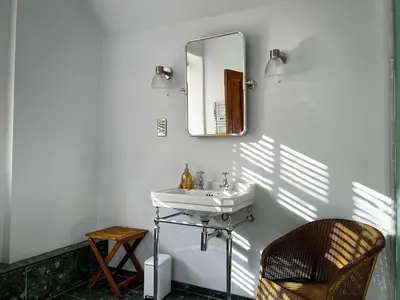 a bathroom with a sink and a mirror and a chair at Coach House in Llanwrtyd Wells