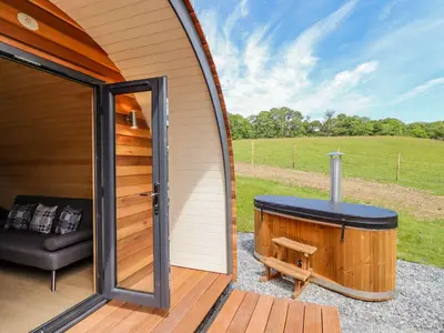 a jacuzzi tub sitting on a deck next to a house at Briallen in Dolgellau