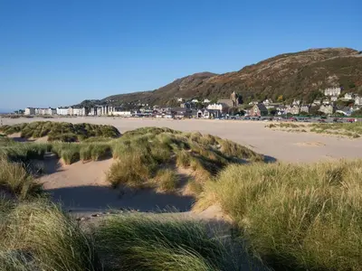 a sandy beach with buildings and houses in the background at Briallen in Dolgellau