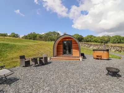 a small wooden cabin with chairs and a grill at Eirlys in Dolgellau