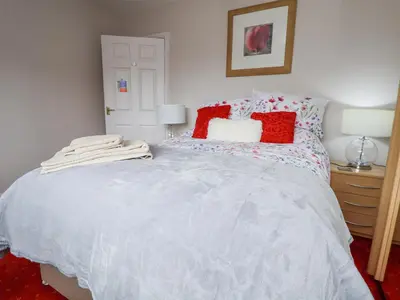 a bedroom with a large white bed with red pillows at 2 Mountain View in Wrexham